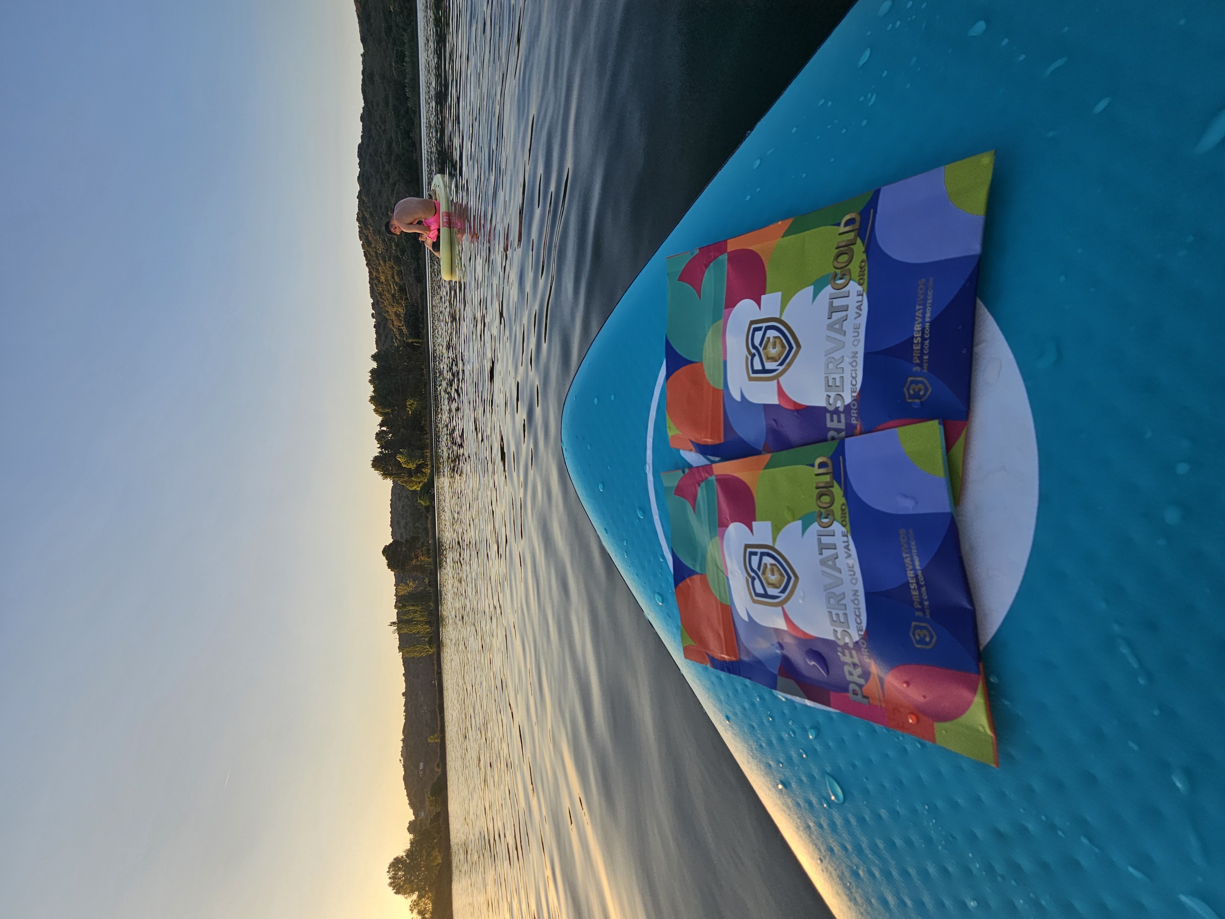 Dos packs PreservatiGold edición limitada colocados sobre una tabla de paddle con gotas de agua, al atardecer en el lago